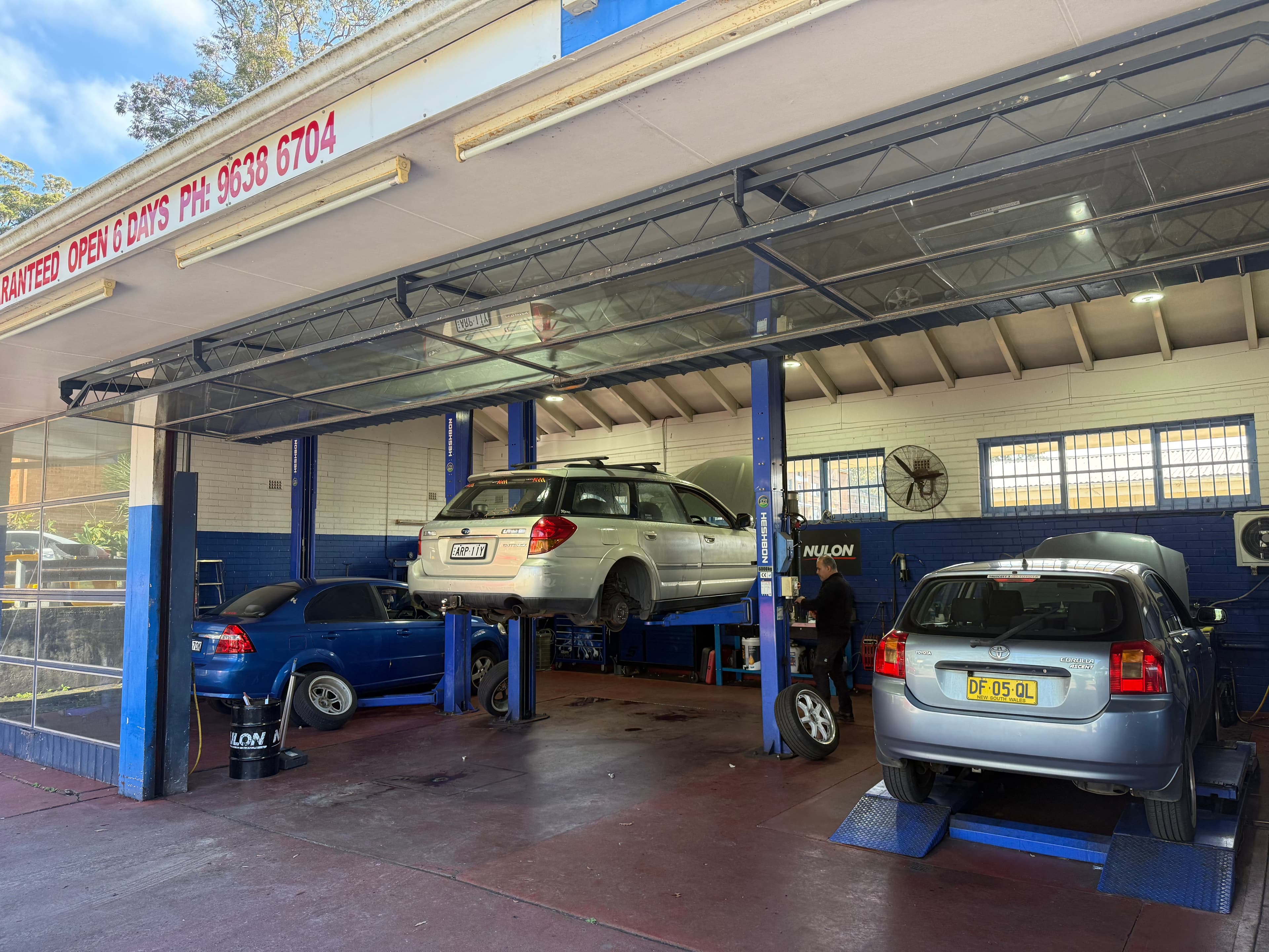 Mechanics working on vehicles raised on workshop lifts